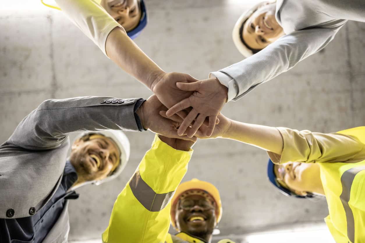 Workers, engineers and architects holding hands together in the building.