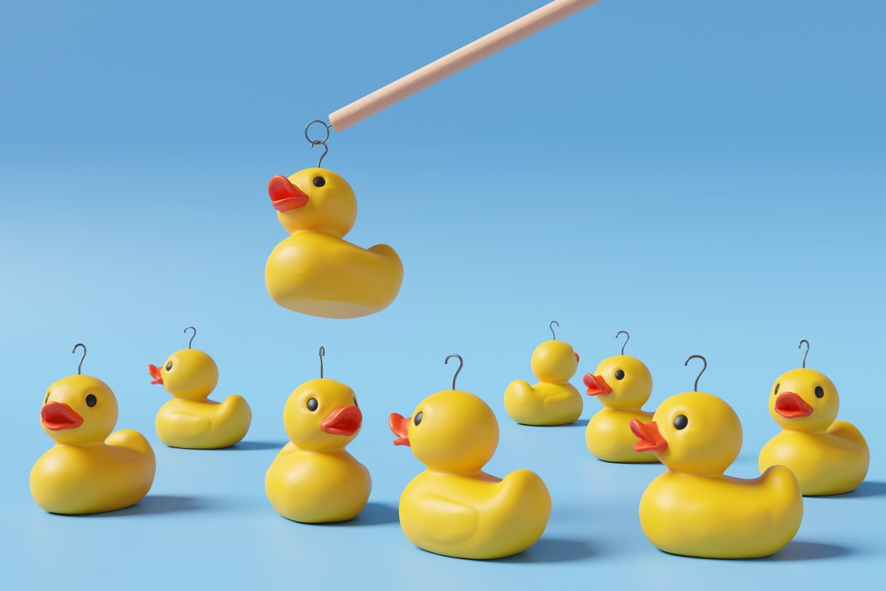 Yellow rubber ducks have metal rings fastened to their heads and one is being hooked on gradient blue background. Illustration of the concept of the traditional fairground stall game hook a duck