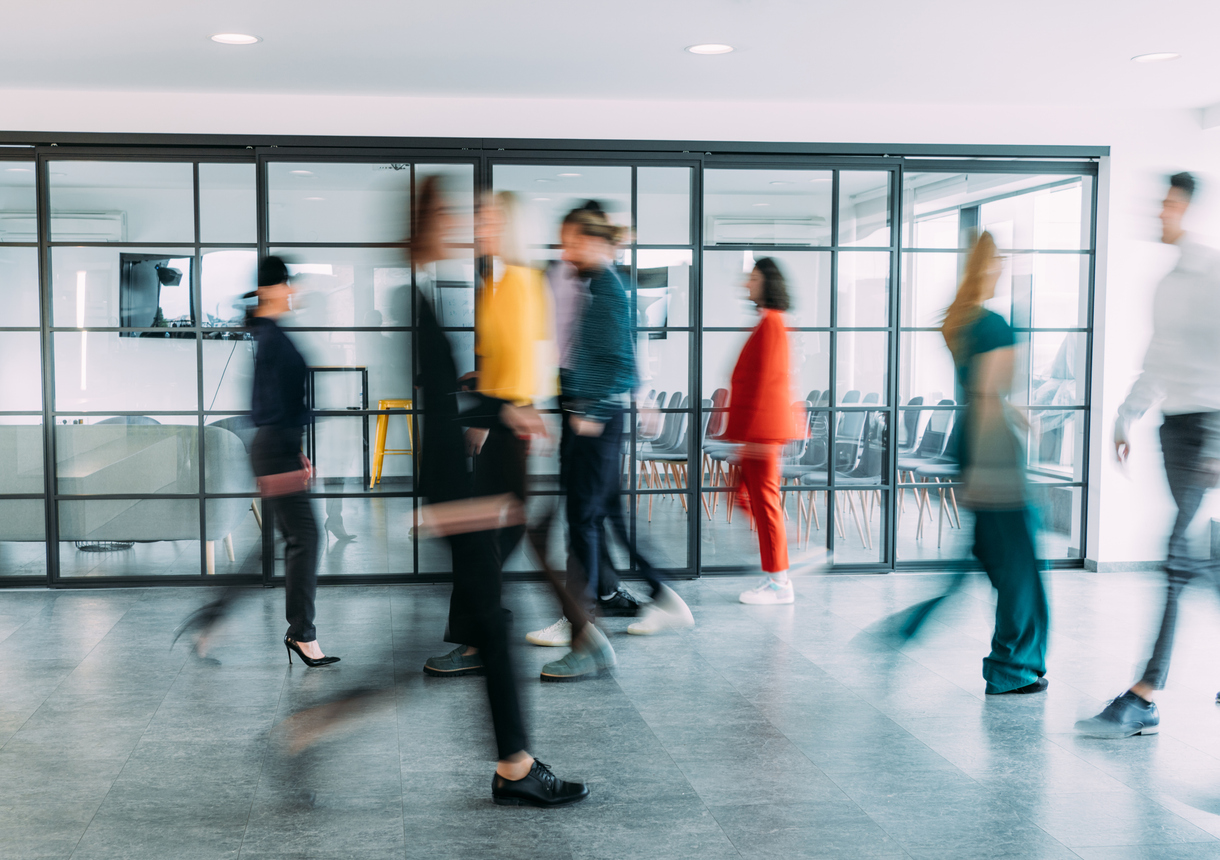 Blurred motion of energetic business people in the office. Shot of business people walking in blurred motion in modern office.
